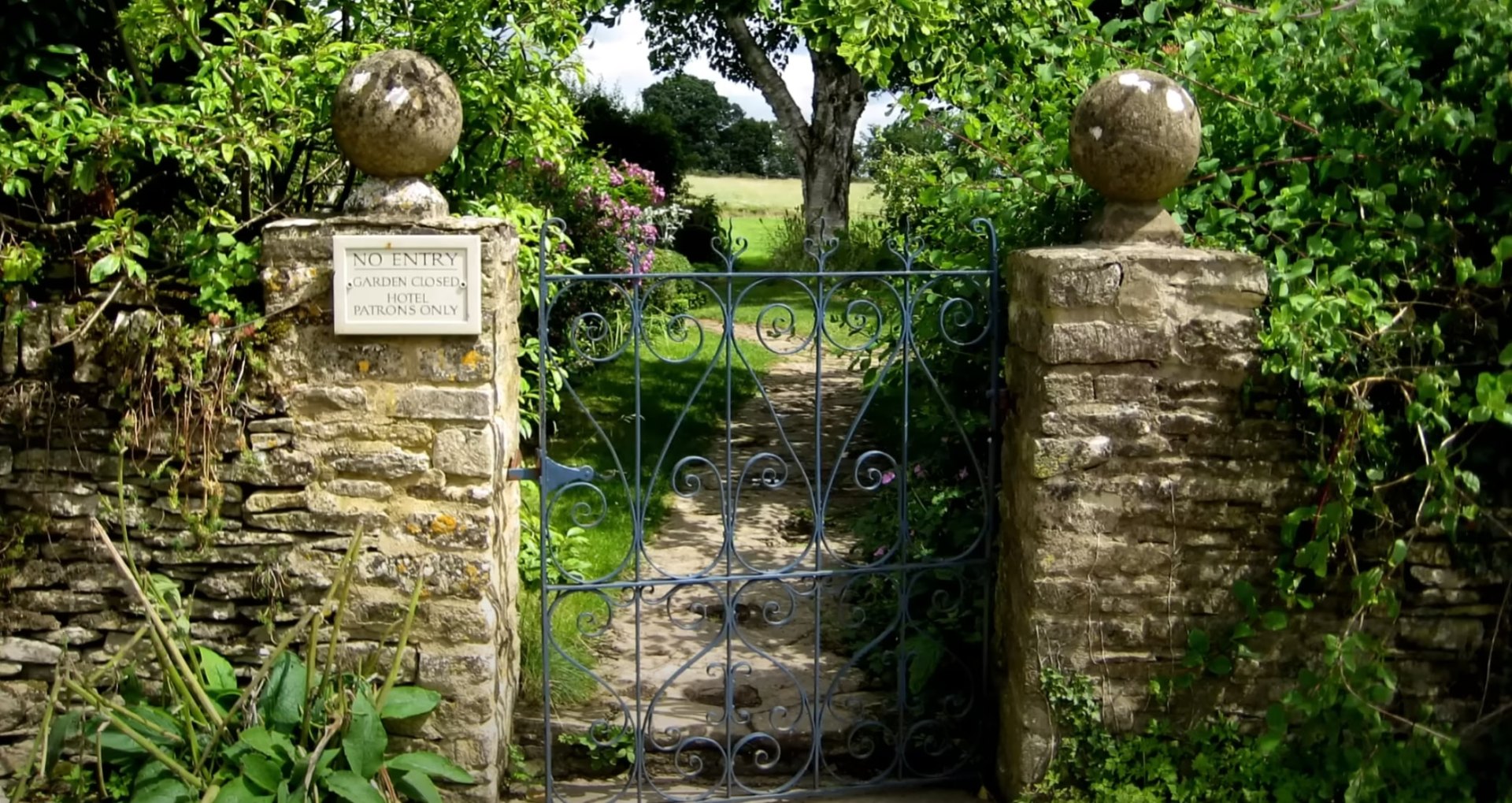 Elegant stone garden gate with professional landscaping and mature trees