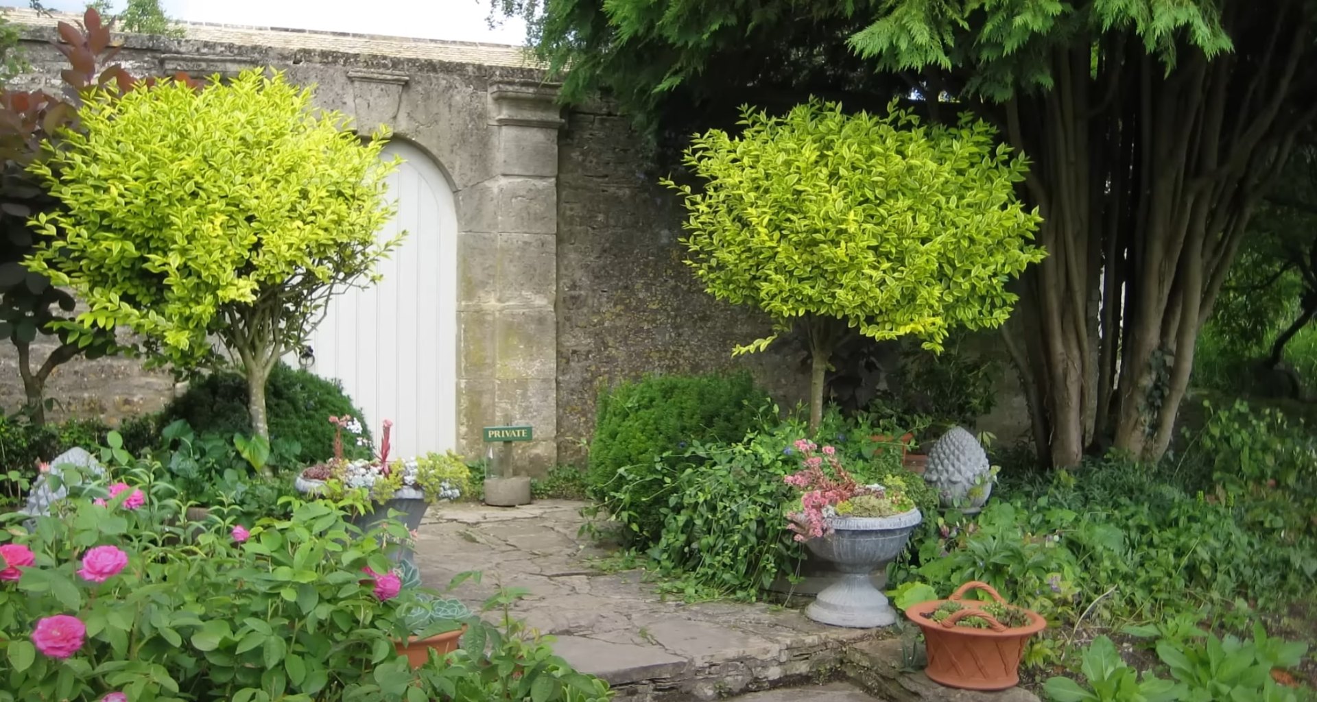 Beautiful garden entrance with stone archway and colorful plantings Charming garden entrance with stone archway