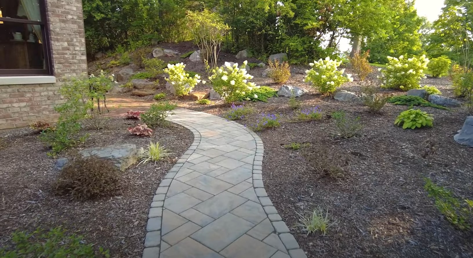 Custom stone walkway with professional garden design Elegant stone walkway with landscaped garden beds